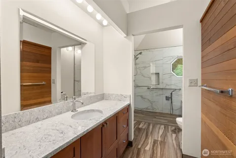 a bathroom with a granite countertop sink a mirror and shower