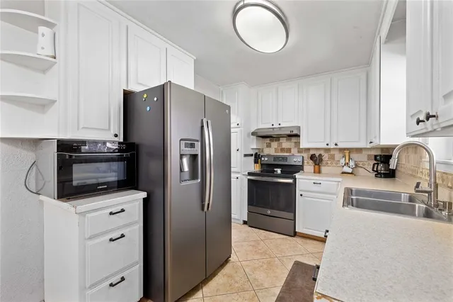 a kitchen with white cabinets and stainless steel appliances