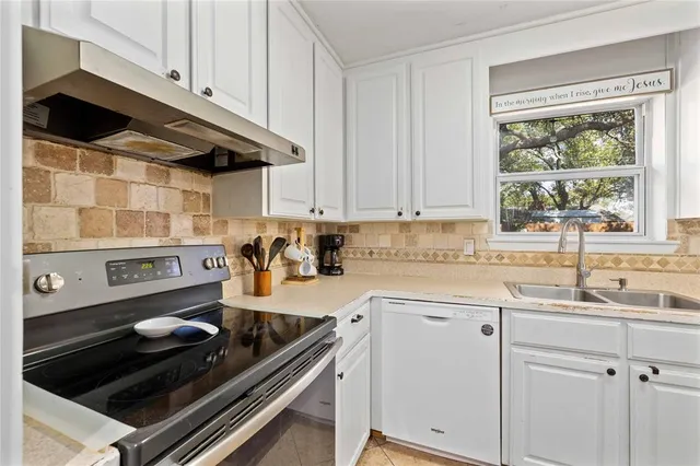 a kitchen with a stove and white cabinets