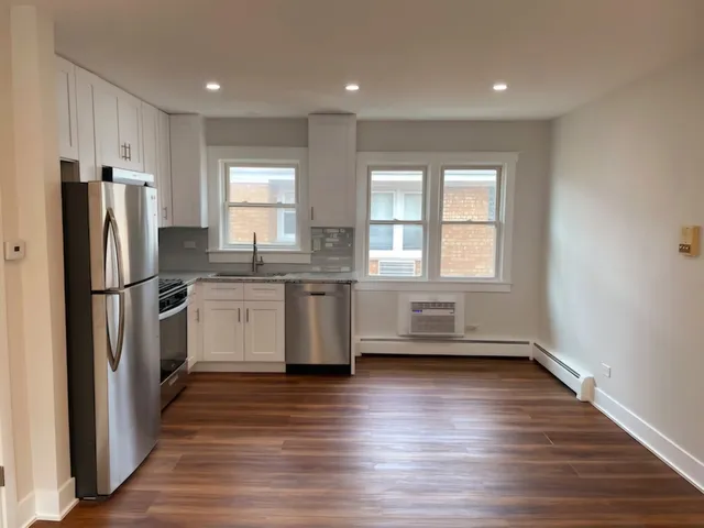 a kitchen with a refrigerator a sink and wooden floor