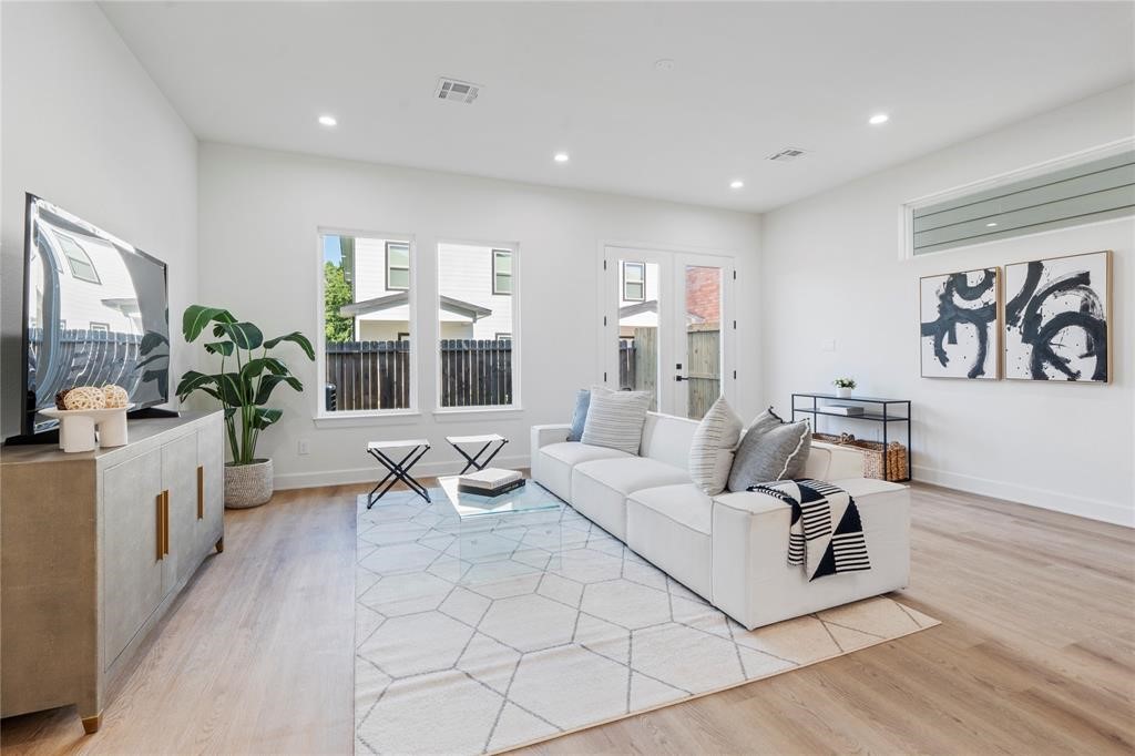 6321 Foster Street Houston, TX 77021 - Photo 7 of 19 Bright and spacious living room featuring sleek hardwood floors, modern furnishings, and abundant natural light from large windows and glass doors.