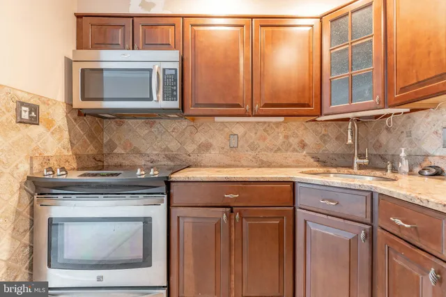 a kitchen with granite countertop white cabinets stainless steel appliances and a counter space