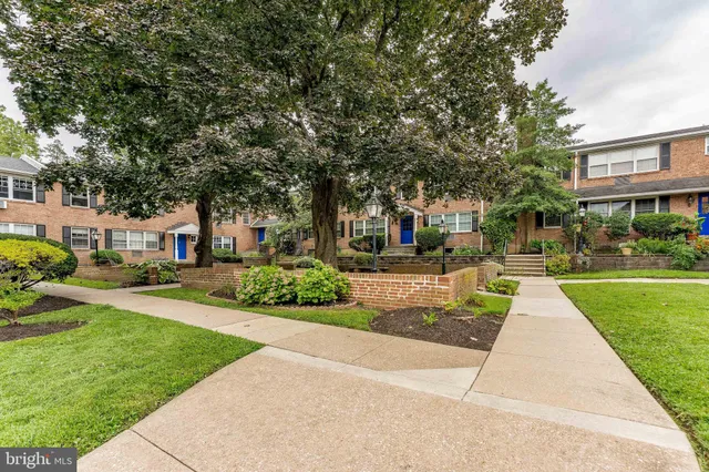 a front view of a building with a garden and trees