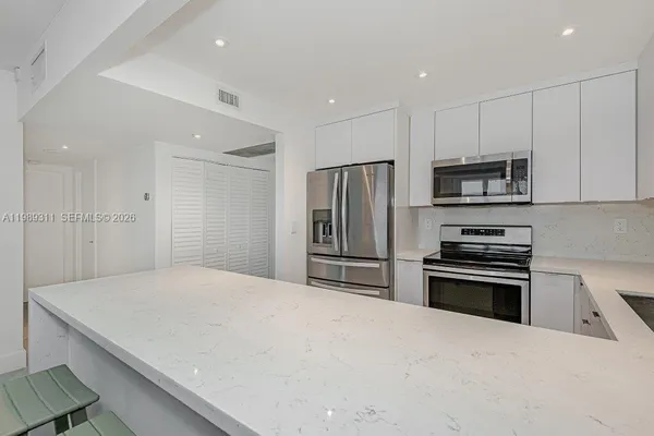 a kitchen with kitchen island a refrigerator stove and microwave
