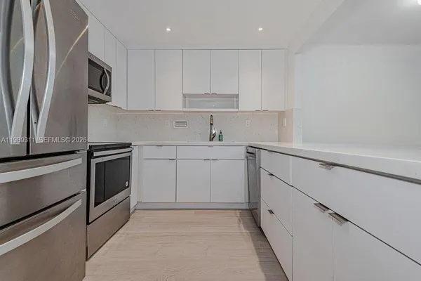 a kitchen with white cabinets stainless steel appliances and sink