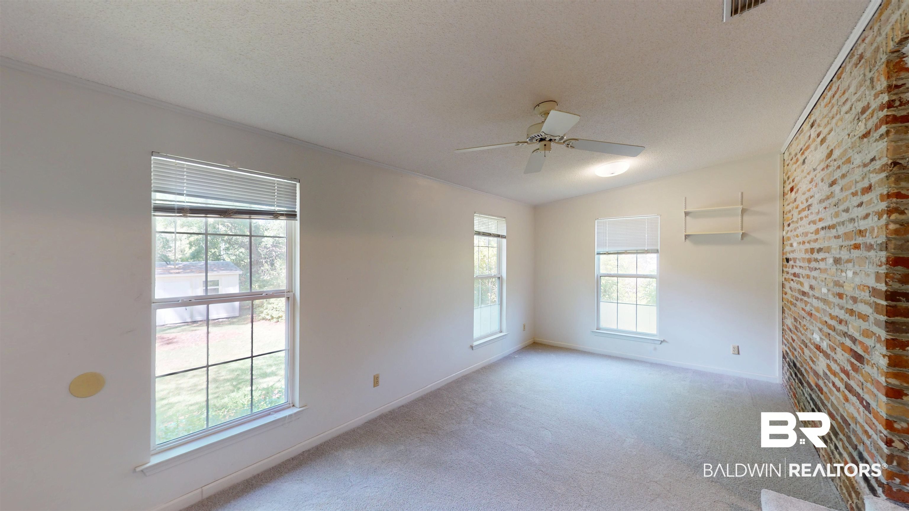 1075 Zurich Street Mobile, AL 36608 - Photo 20 of 35 Empty room featuring brick wall, light carpet, a ceiling fan, and a textured ceiling