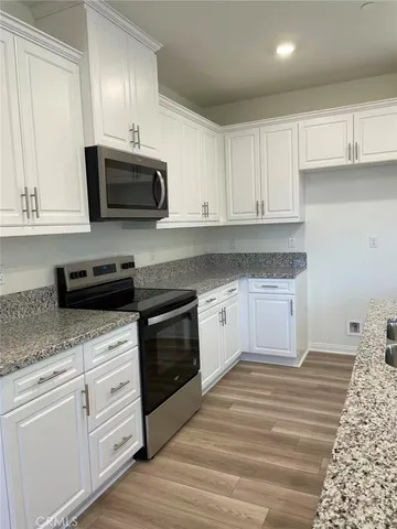 a kitchen with granite countertop white cabinets white stainless steel appliances and a sink