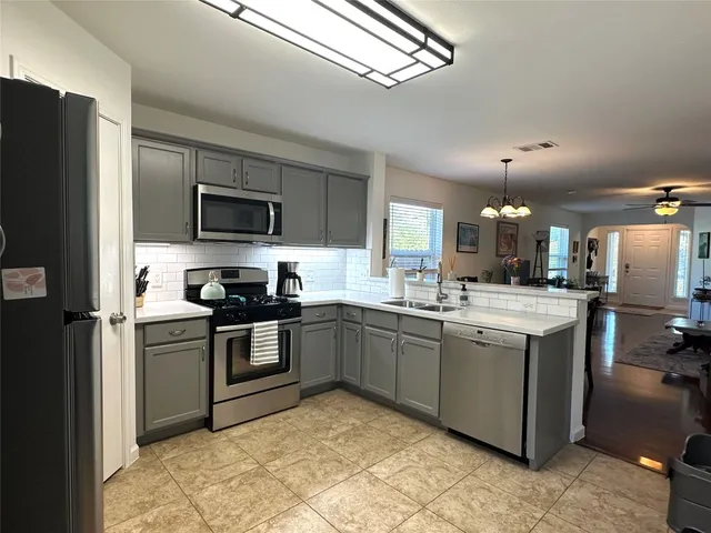 a kitchen with stainless steel appliances granite countertop a sink a stove a refrigerator and black cabinets