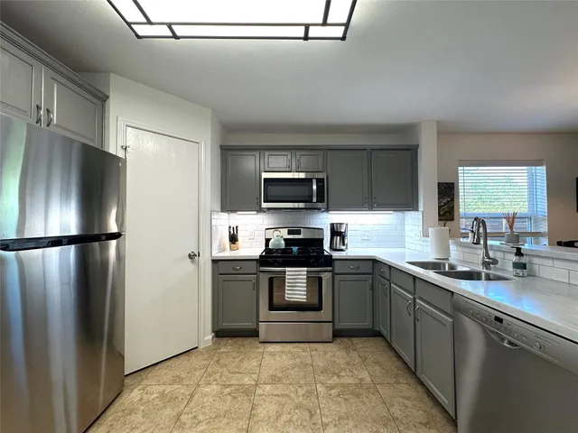 a kitchen with stainless steel appliances granite countertop a refrigerator a sink a stove top oven and a dishwasher