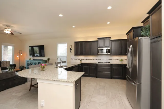 a kitchen with kitchen island granite countertop a stove a sink and a refrigerator