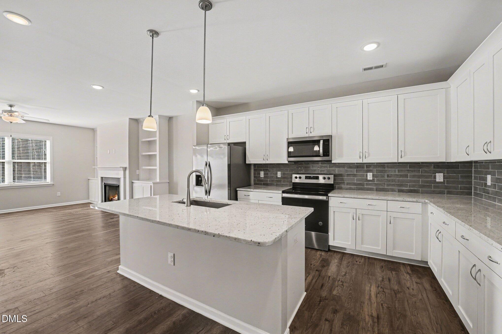 106 Two Daughters Streme Smithfield, NC 27577 - Photo 12 of 25 a kitchen with stainless steel appliances granite countertop a sink a stove a refrigerator and white cabinets with wooden floor