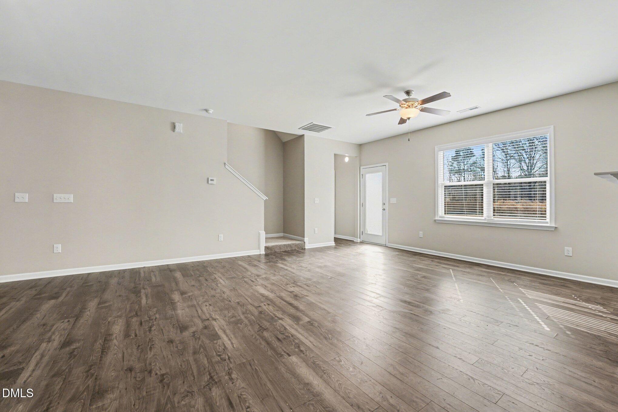 106 Two Daughters Streme Smithfield, NC 27577 - Photo 4 of 25 an empty room with wooden floor chandelier and windows