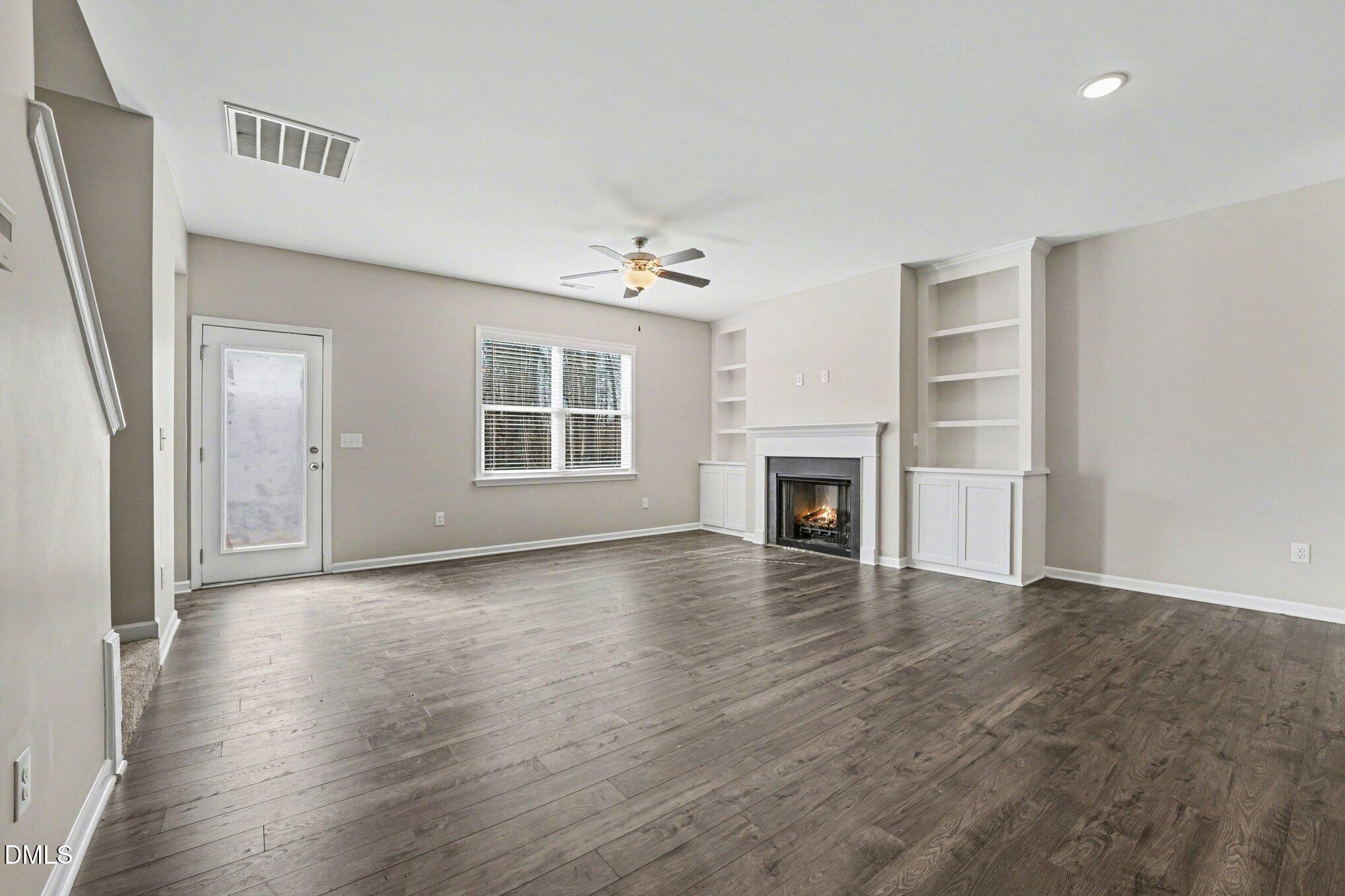 106 Two Daughters Streme Smithfield, NC 27577 - Photo 5 of 25 an empty room with wooden floor fireplace and windows