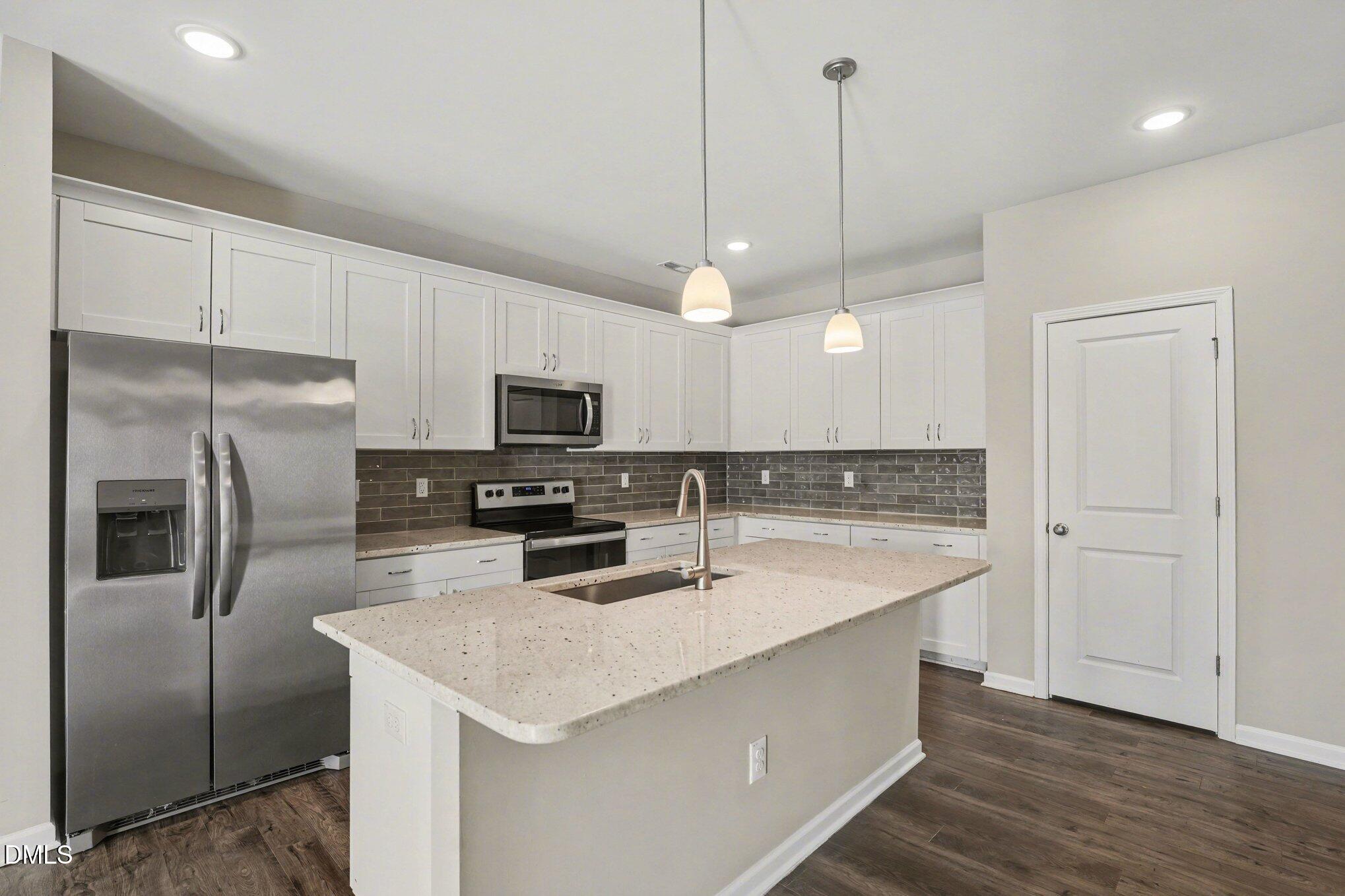 106 Two Daughters Streme Smithfield, NC 27577 - Photo 10 of 25 a kitchen with stainless steel appliances granite countertop a sink a stove a refrigerator a center island with wooden floor