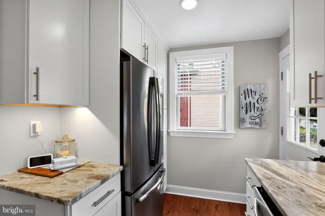 a kitchen with granite countertop white cabinets and refrigerator