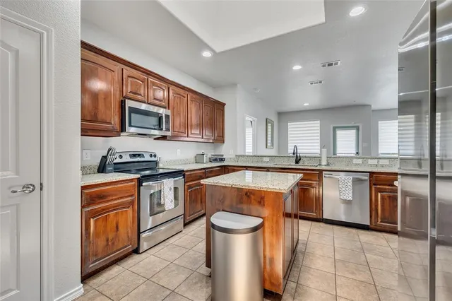 a kitchen with stainless steel appliances granite countertop a stove a sink and a microwave