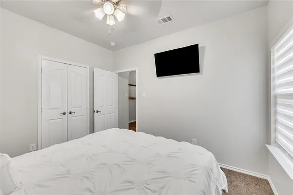 a bedroom with a bed tv and a window