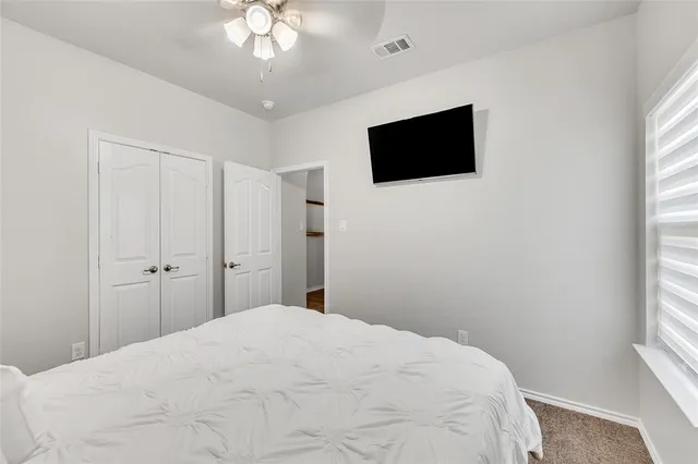 a bedroom with a bed tv and a window