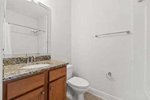 a bathroom with a granite countertop sink and a toilet
