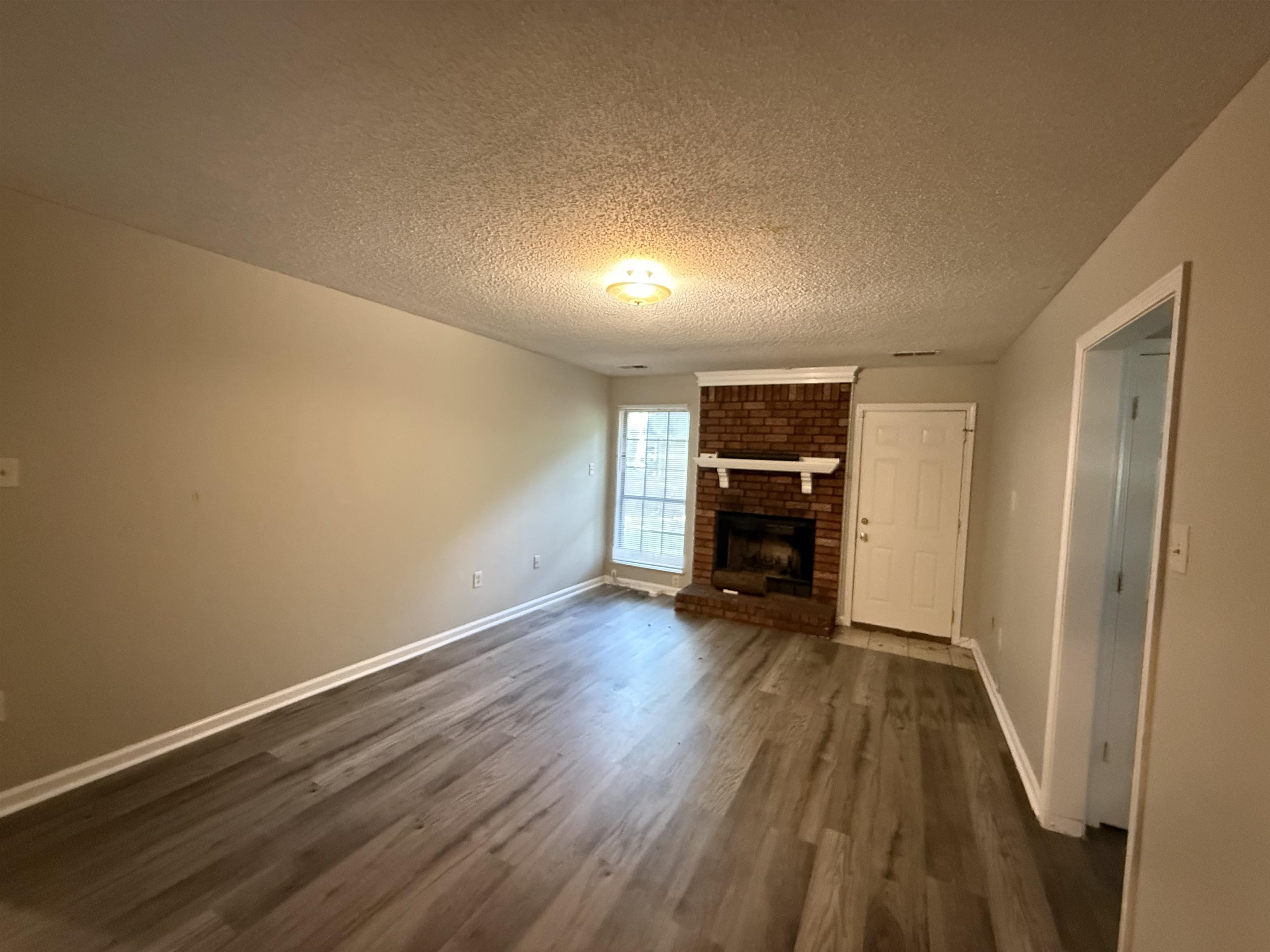 6420 Saginaw Road Memphis, TN 38134 - Photo 2 of 38 Living area featuring wood-finish flooring, a brick fireplace with a white mantel, neutral wall paint, and white trim