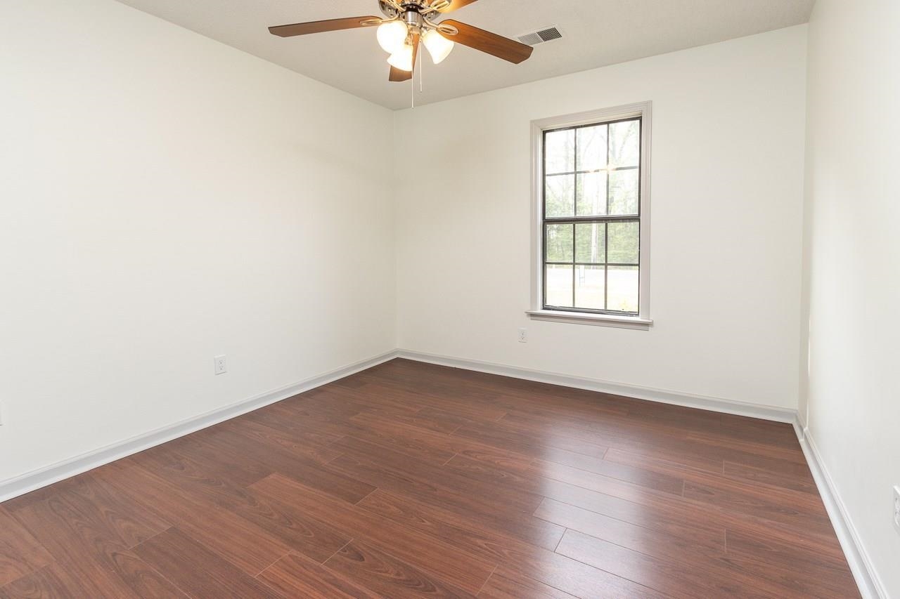 7882 Macon Road Memphis, TN 38018 - Photo 8 of 13 an empty room with wooden floor chandelier fan and windows