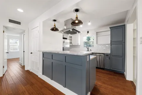 a kitchen with a refrigerator and countertop white cabinets