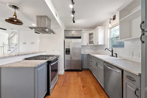 a kitchen with stainless steel appliances granite countertop a sink a stove and a refrigerator