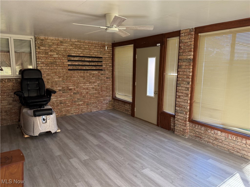 683 Robinson Road Campbell, OH 44405 - Photo 6 of 23 Unfurnished living room with brick wall, a ceiling fan, and wood finished floors