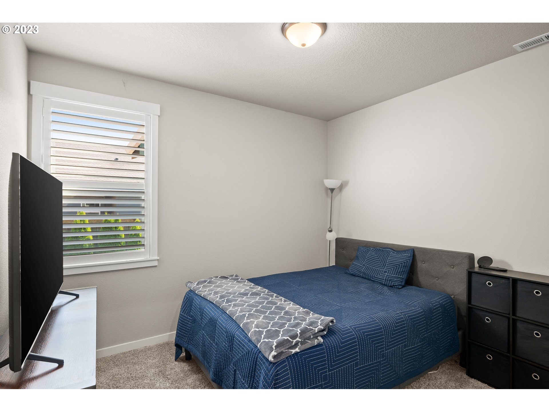 16316 Kitty Hawk Avenue Oregon City, OR 97045 - Photo 21 of 29 a bedroom with a bed and a flat tv screen on a dresser