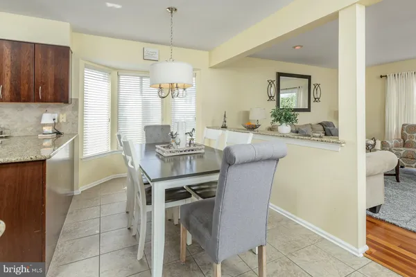 a dining room with stainless steel appliances kitchen island granite countertop a table chairs and a refrigerator