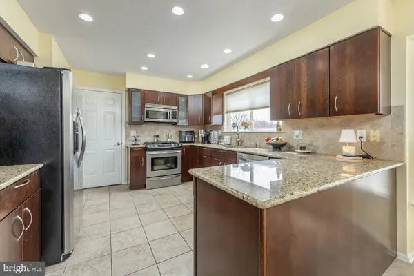 a kitchen with stainless steel appliances kitchen island granite countertop a refrigerator and a stove top oven