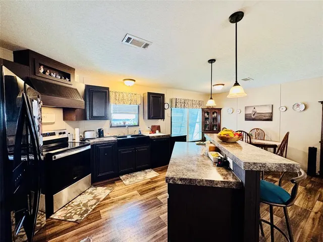 a large kitchen with kitchen island a stove a refrigerator a sink dishwasher with a dining table and chairs with wooden floor