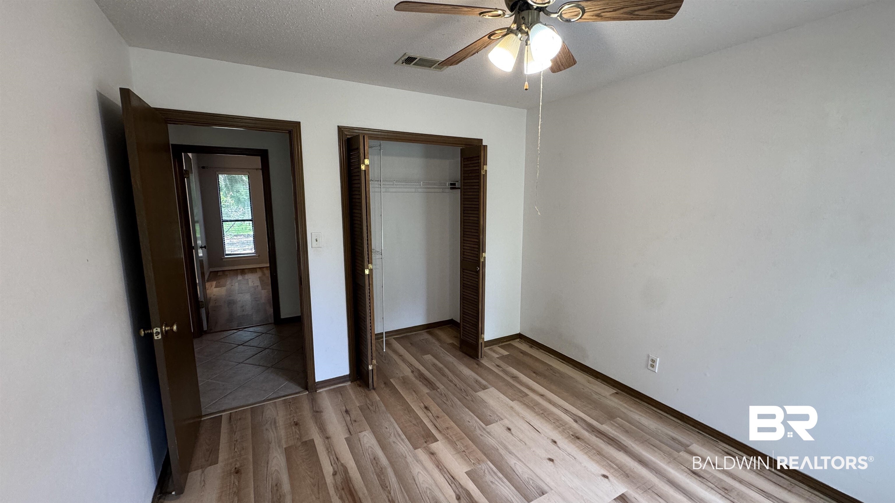 33370 Highway 98 Lillian, AL 36549 - Photo 33 of 58 Room featuring wood-finish flooring, white walls, and a ceiling fan with integrated lighting
