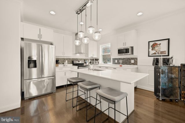 a kitchen with kitchen island white cabinets and stainless steel appliances