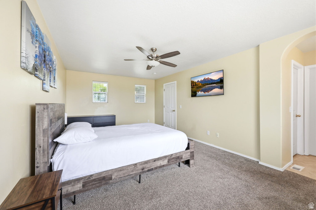 5485 Heather Way Tooele, UT 84074 - Photo 24 of 41 Spacious room featuring neutral-toned walls, textured carpeting, two windows providing natural light, a ceiling fan with light fixture, and an arched doorway