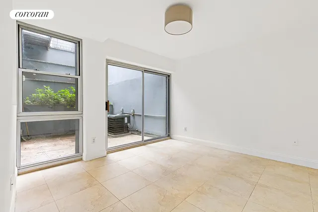 an empty room with floor to ceiling fan and window