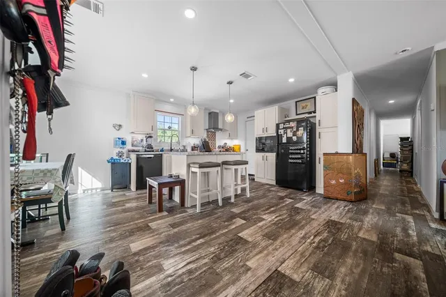 a kitchen with stainless steel appliances kitchen island granite countertop a table chairs and a refrigerator
