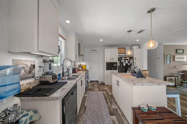 a kitchen with stainless steel appliances granite countertop a sink a stove and cabinets