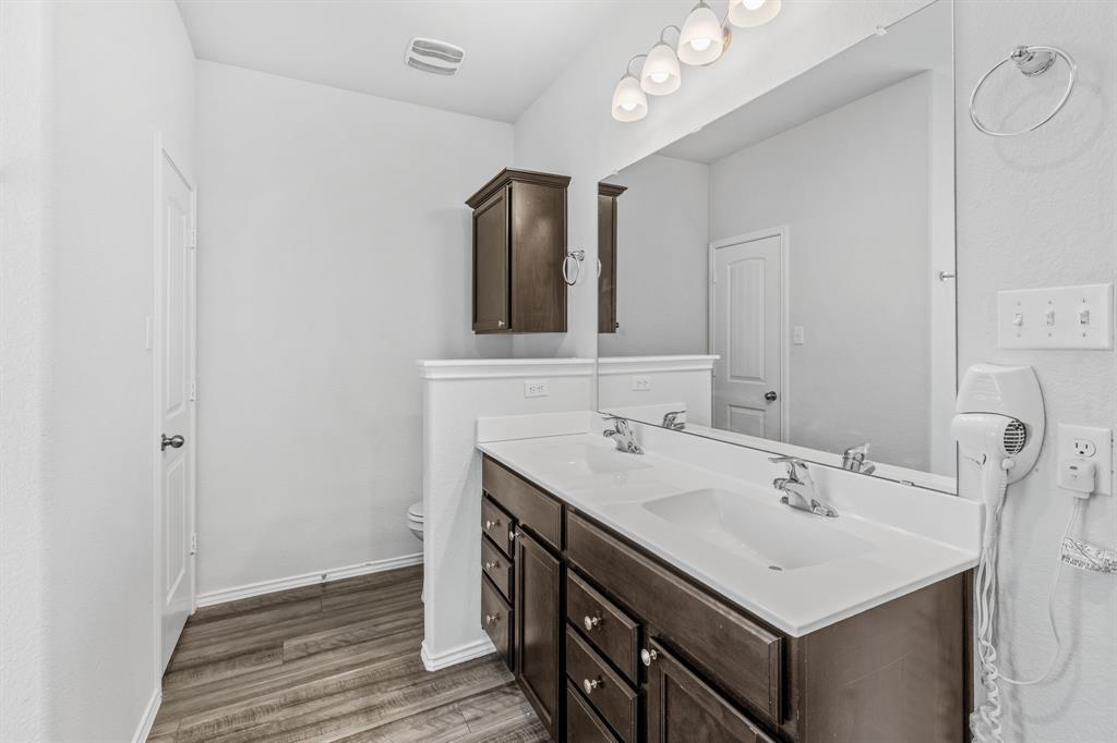 11101 Beckon Waco, TX 76708 - Photo 20 of 35 Dual vanity with integrated sinks, wood-finish flooring, dark wood cabinetry, and a large wall-mounted mirror