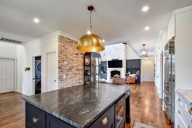 a kitchen with kitchen island granite countertop a stove a sink and a wooden floors