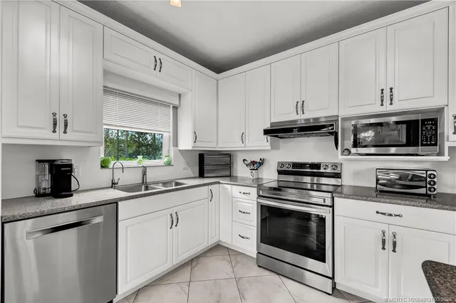 a kitchen with cabinets stainless steel appliances a sink a window and cabinets