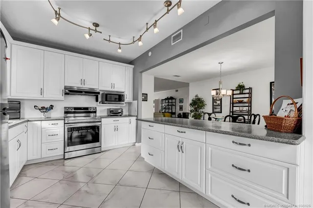a kitchen with granite countertop white cabinets and white stainless steel appliances