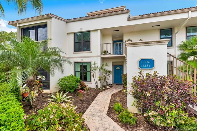 a view of a white house with large windows and potted plants