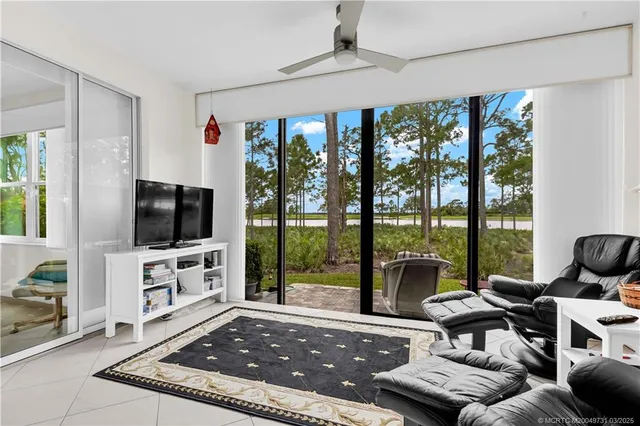 a living room with furniture a flat screen tv and floor to ceiling window