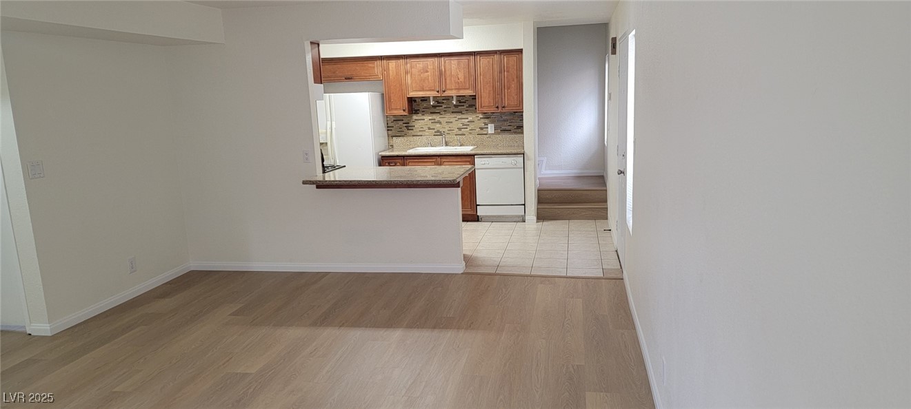 5196 Golden Lane, Unit C Las Vegas, NV 89119 - Photo 11 of 29 Kitchen featuring white appliances, backsplash, light wood-style floors, brown cabinets, and light countertops