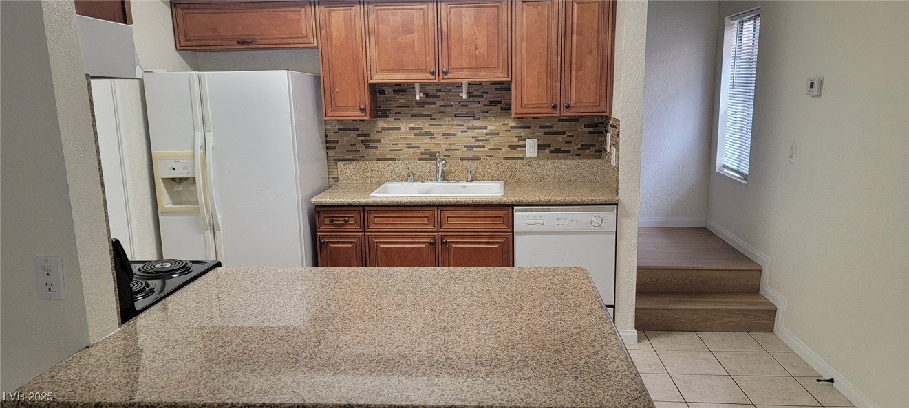 5196 Golden Lane, Unit C Las Vegas, NV 89119 - Photo 12 of 29 Kitchen featuring white appliances, tasteful backsplash, light tile patterned flooring, and brown cabinets