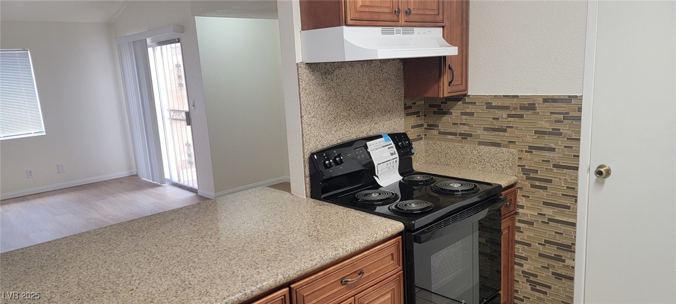 5196 Golden Lane, Unit C Las Vegas, NV 89119 - Photo 15 of 29 Kitchen with black / electric stove, custom range hood, backsplash, wood finished floors, and light countertops