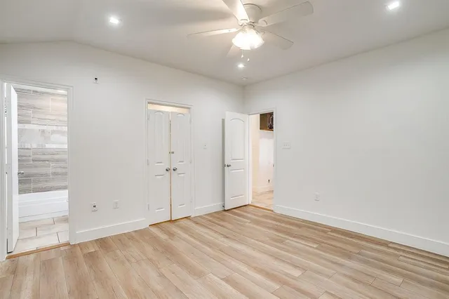 an empty room with a ceiling fan and wooden floor