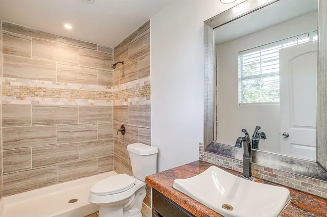 a bathroom with a sink a toilet a mirror and shower