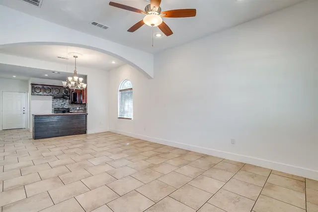 an empty room with chandelier fan and windows